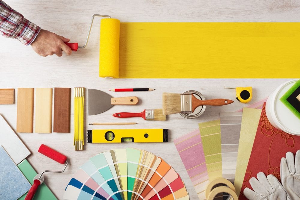 Graphic to show decorator holding a painting roller and painting a wooden surface, work tools and swatches at bottom, banner with copy space